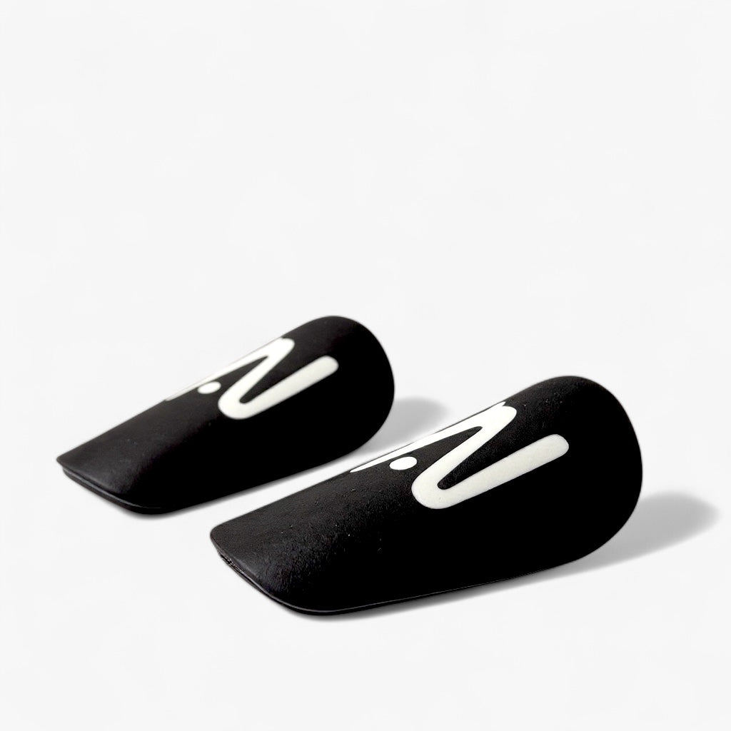 Pair of black shin guards with white logo on a light gray background
