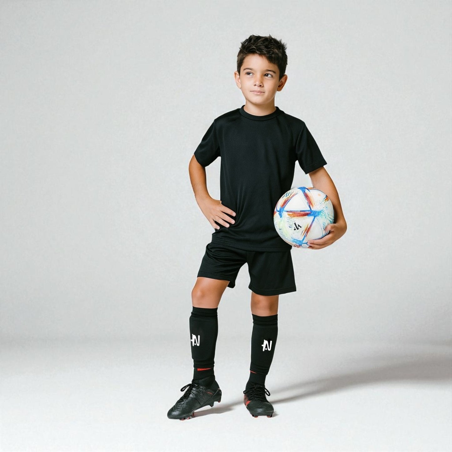 Child in black soccer uniform holding a soccer ball on a white background