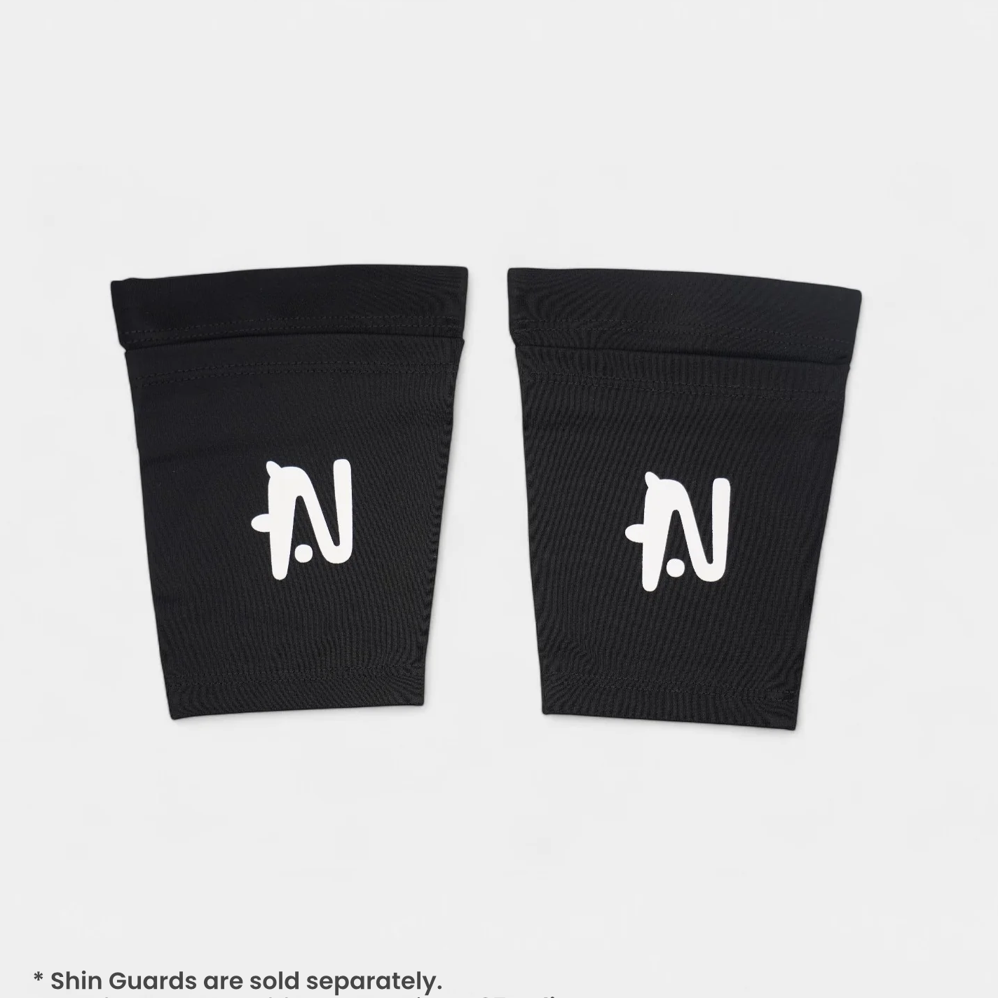 Two black shin guard sleeves with a logo on a white background. Text says shin guards sold seperatley