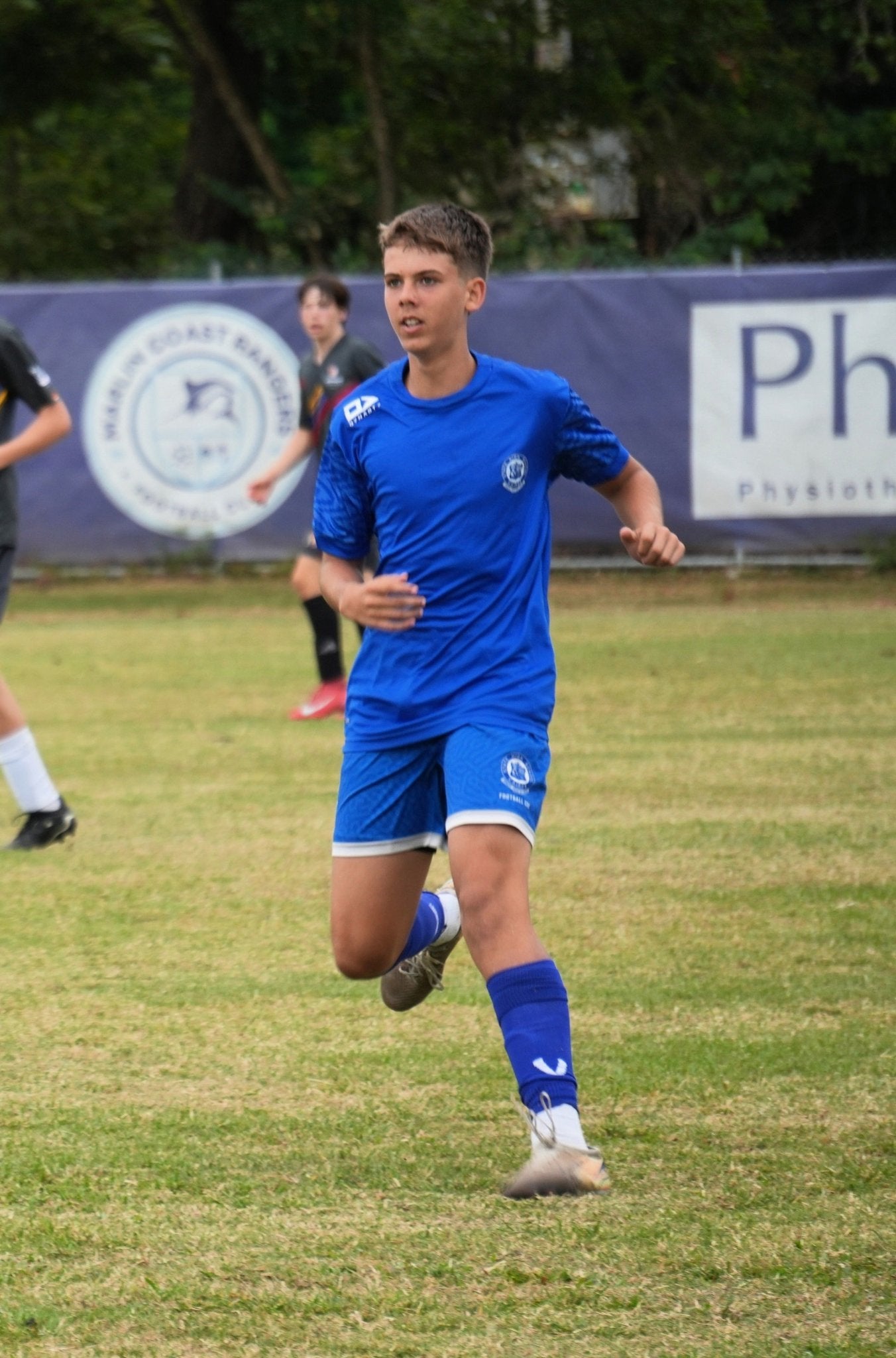 Soccer player in blue uniform running on a field with a blurred background