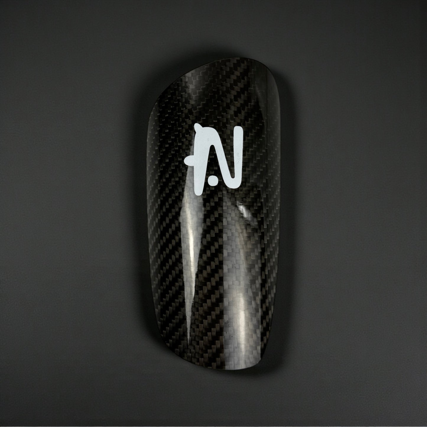 Carbon Fiber Shin Guard with a logo on a dark background