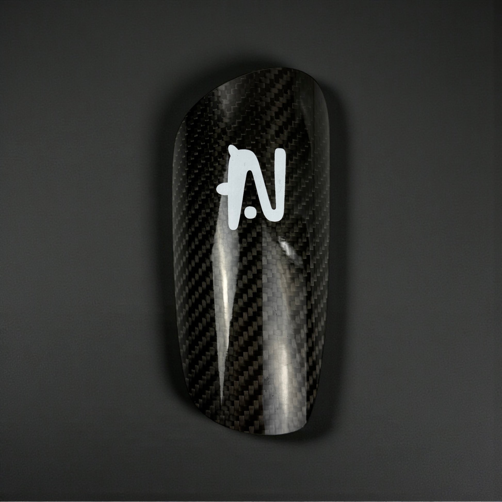 Carbon Fiber Shin Guard with a logo on a dark background