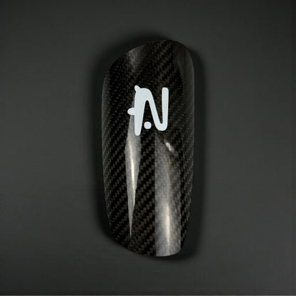 Carbon Fiber Shin Guard with a logo on a dark background