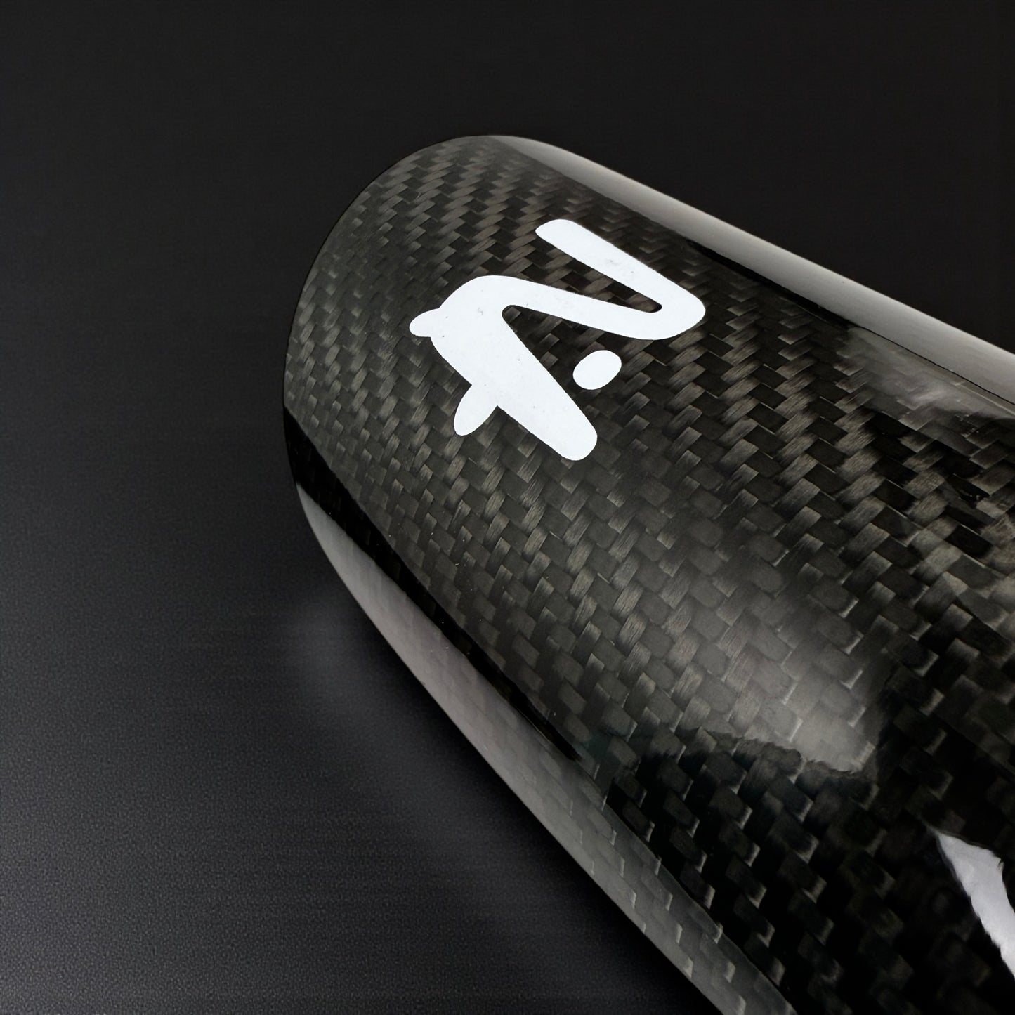 Carbon fiber surface with a white logo on a black background
