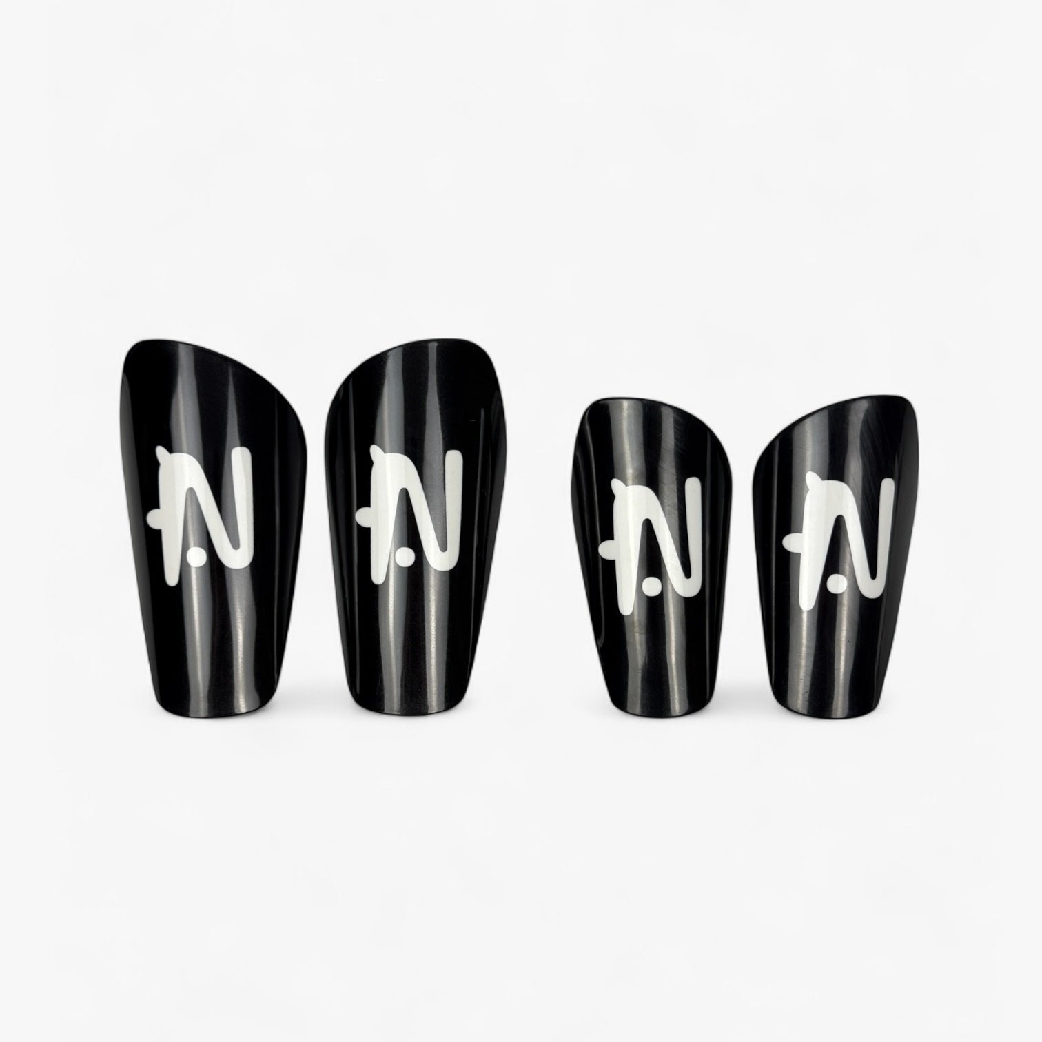 Four black NTMG shin guards with white logo on a white background