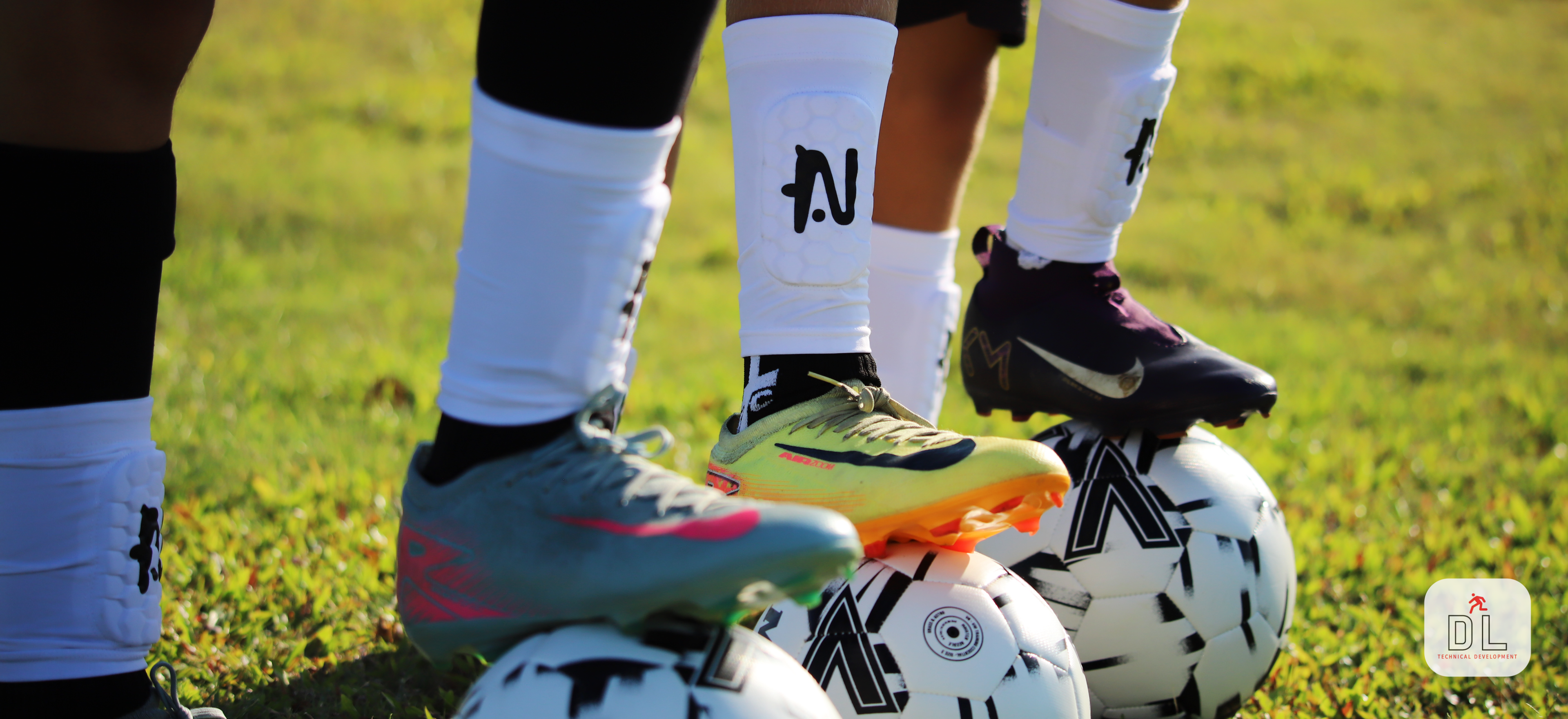 Soccer players on a field with soccer balls wearing White NTMG Built In Shin Pads