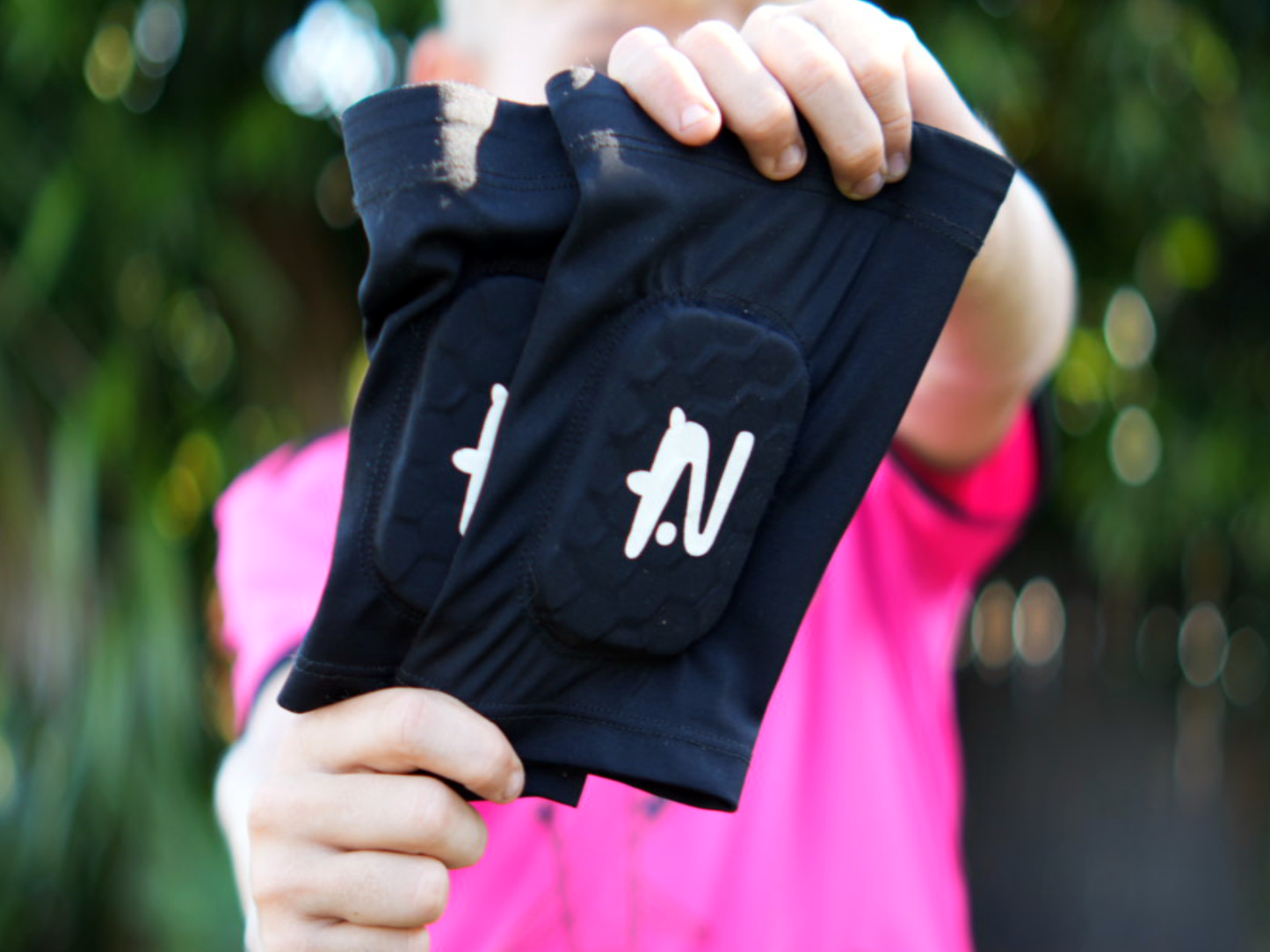 Child in pink soccer jersey holds up black NTMG and stretches them